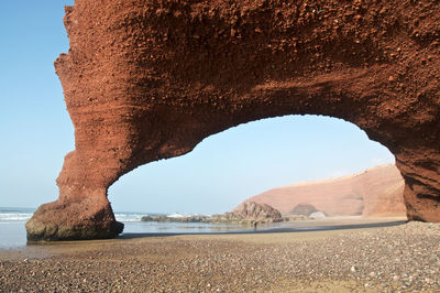 Natural arch at beach against sky