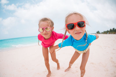 Portrait of happy friends on beach against sky