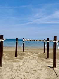 Wooden posts on beach against sky