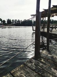 Wooden post by lake against sky
