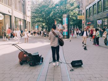 Rear view of woman playing guitar at city street