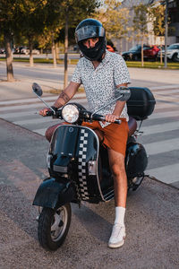 Young handsome male with hipster outfit rides a black vintage motorbike. he is a caucasian   male 