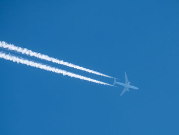 Low angle view of airplane flying against clear blue sky