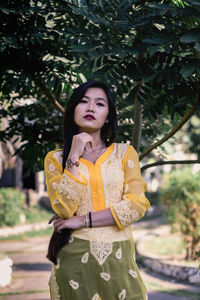 Portrait of woman standing against tree