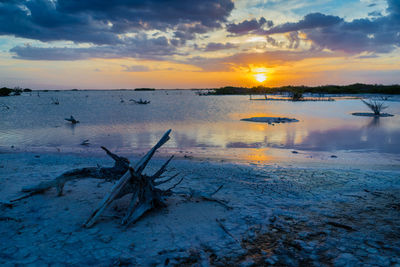 Scenic view of sea against cloudy sky at sunset