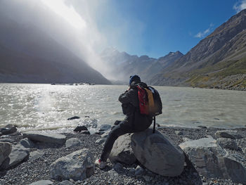 Rear view of man looking at snowcapped mountain against sky