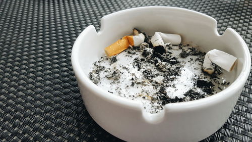 High angle view of cigarette butts in ashtray on table
