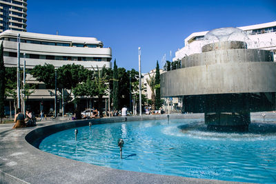 People sitting by pool and fountain