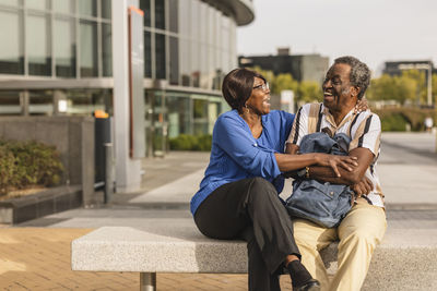 Senior couple laughing with each other sitting on bench