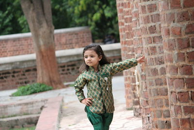 Full length of boy standing against brick wall