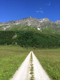 Empty road leading towards green majestic mountains