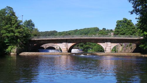 Arch bridge over river against sky