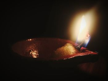 Close-up of illuminated burning candle against black background