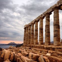 Temple of poseidon against cloudy sky