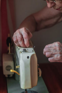 Midsection of senior woman operating sewing machine at home