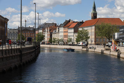 Buildings by river against sky