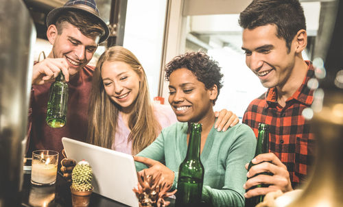 Smiling friends using digital tablet in restaurant