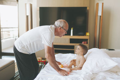 Grandfather playing with a baby at home sticking out tongue