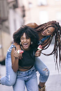 Cheerful woman piggybacking friend in city