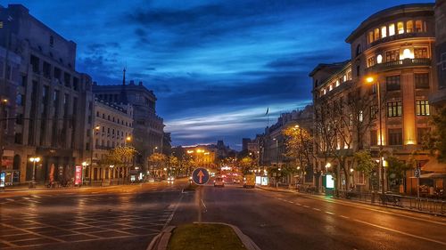 Illuminated city street and buildings at dusk