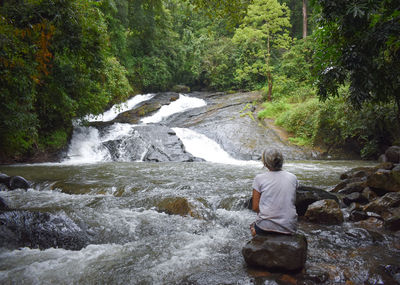 Rear view of man standing in waterfall
