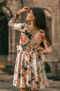 Woman in dress standing against building