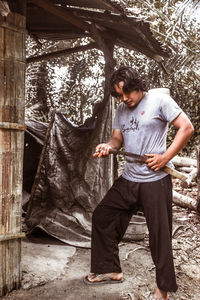 Full length of young man standing against trees