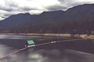 Scenic view of lake and mountains against cloudy sky