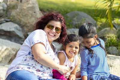 Cheerful family sitting on rock at park