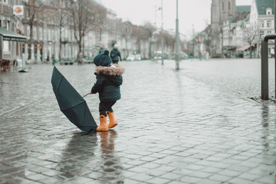 Cute boy playing with an umbrella under the rain