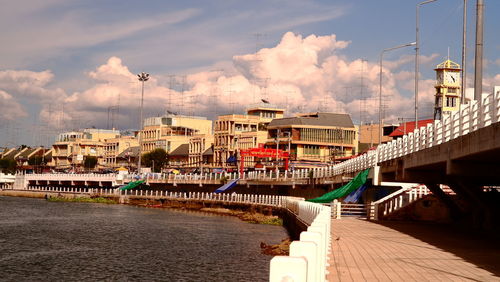 Bridge over river by buildings in city against sky