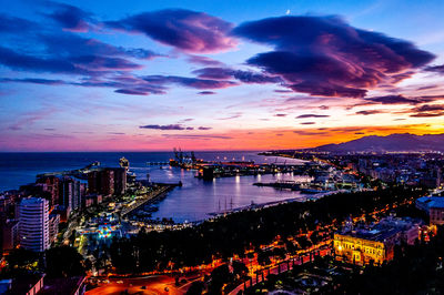 High angle view of city by sea against sky at sunset
