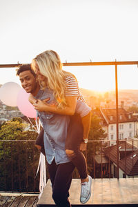 Young couple standing on balcony against clear sky