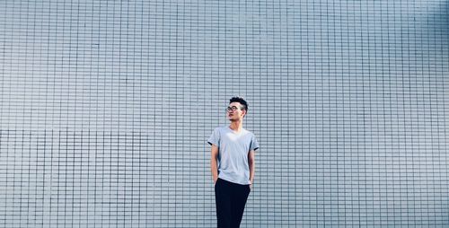 Woman looking away while standing against wall