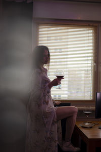 Side view of woman using mobile phone at home