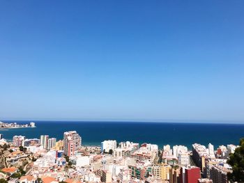 Panoramic view of sea and buildings against clear blue sky