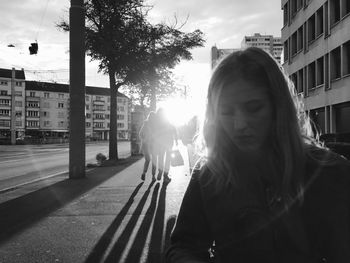 Young woman on sidewalk in city during sunny day