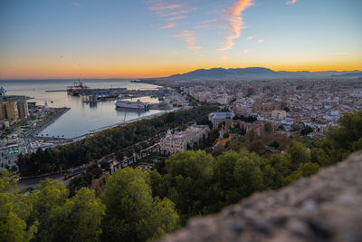 High angle view of townscape by sea against sky during sunset