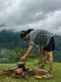 Side view of young man standing on land against sky