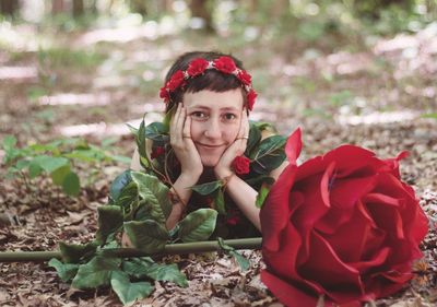 Portrait of smiling young woman with red flowers on land