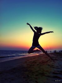 Woman jumping on beach at sunset