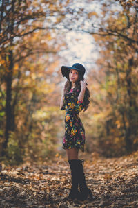 Portrait of woman standing by tree in forest