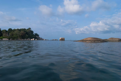 Rocks in sea against cloudy sky