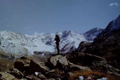 Man standing on rock against sky