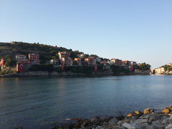 Buildings by sea against clear sky