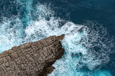 High angle view of sea waves splashing on rocks