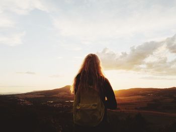 Rear view of woman standing on landscape against sky