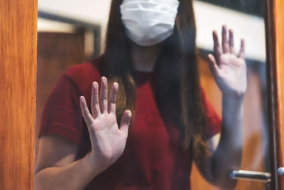 Midsection of woman wearing mask looking through window