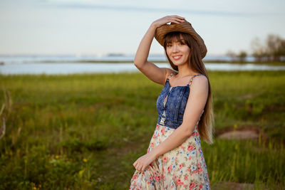 Portrait of young happy woman in straw hat on nature near water