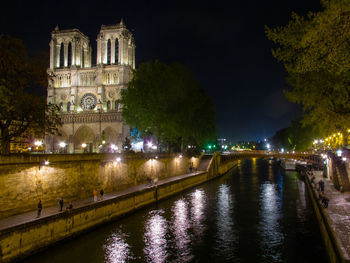 Illuminated building by river at night